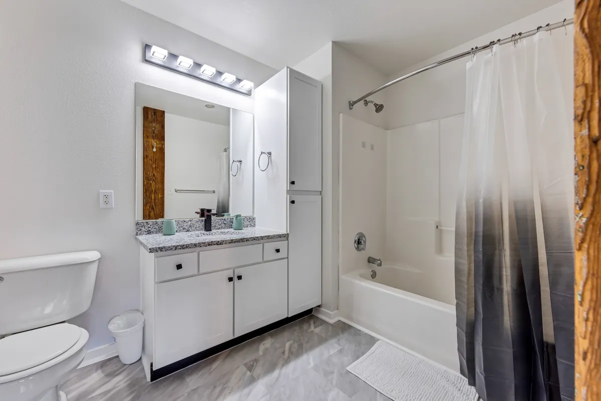 A fresh, modern bathroom with sleek granite countertops, a wide mirror, and a glass-enclosed shower. The space is bright and inviting, suggesting spa-like touches and a private retreat for relaxation and rejuvenation.