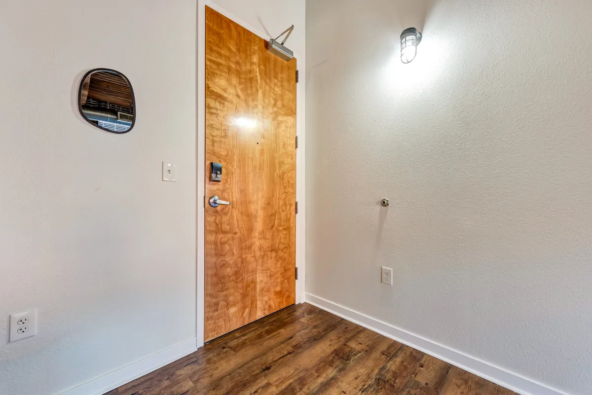 A close-up view of the welcoming entryway, featuring a striking wooden door, a wall-mounted light fixture, and a mirror that hints at thoughtful design. The scene evokes the experience of arriving home, setting the stage for the historic welcome described in the section.
